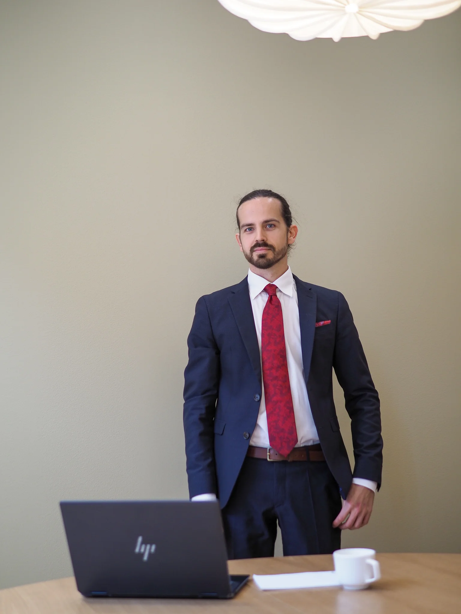 Mies seisoo toimistossa kannettavan tietokoneen vieressä.